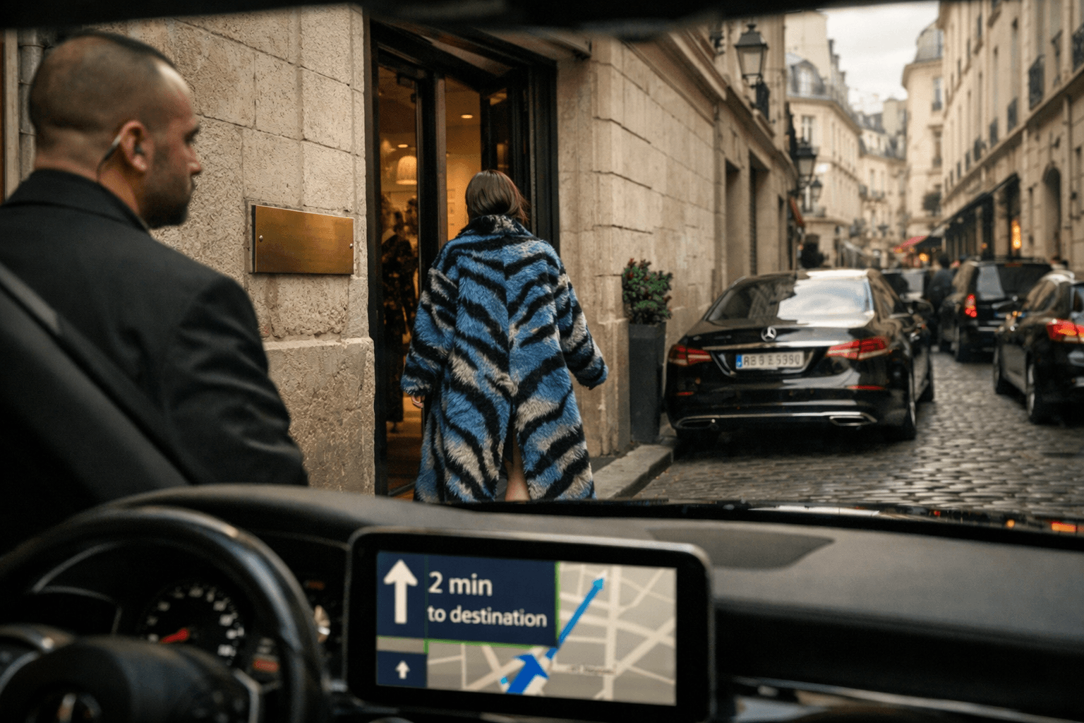 () dynamic street-level photograph from chauffeur perspective through windshield: view of exclusive Marais showroom entrance